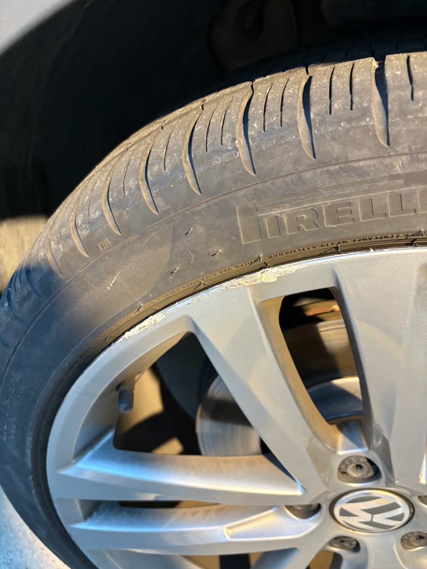 Curbed Volkswagen alloy wheel with chunks of metal missing from the rim lip
