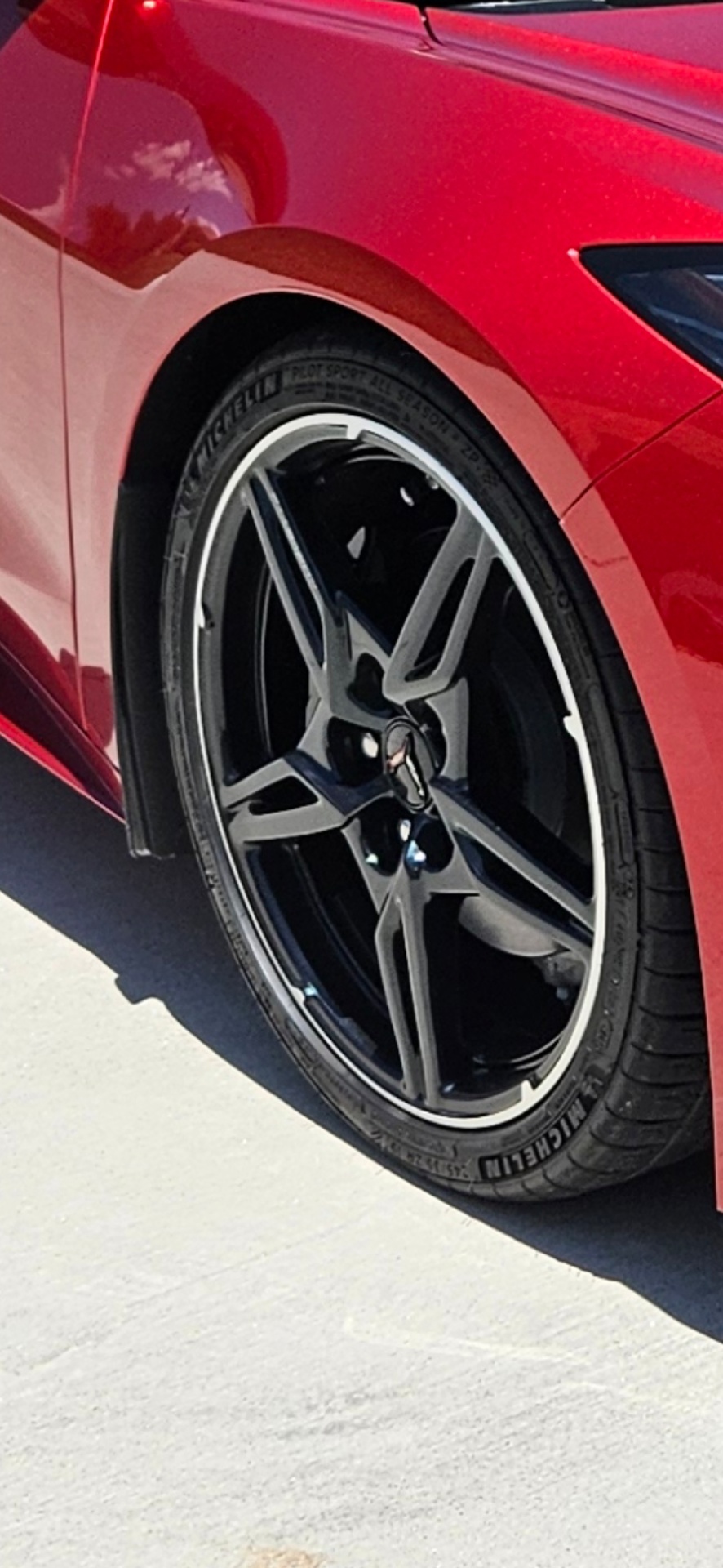 Black AMG wheel with chipped paint around the lip on a red Mercedes