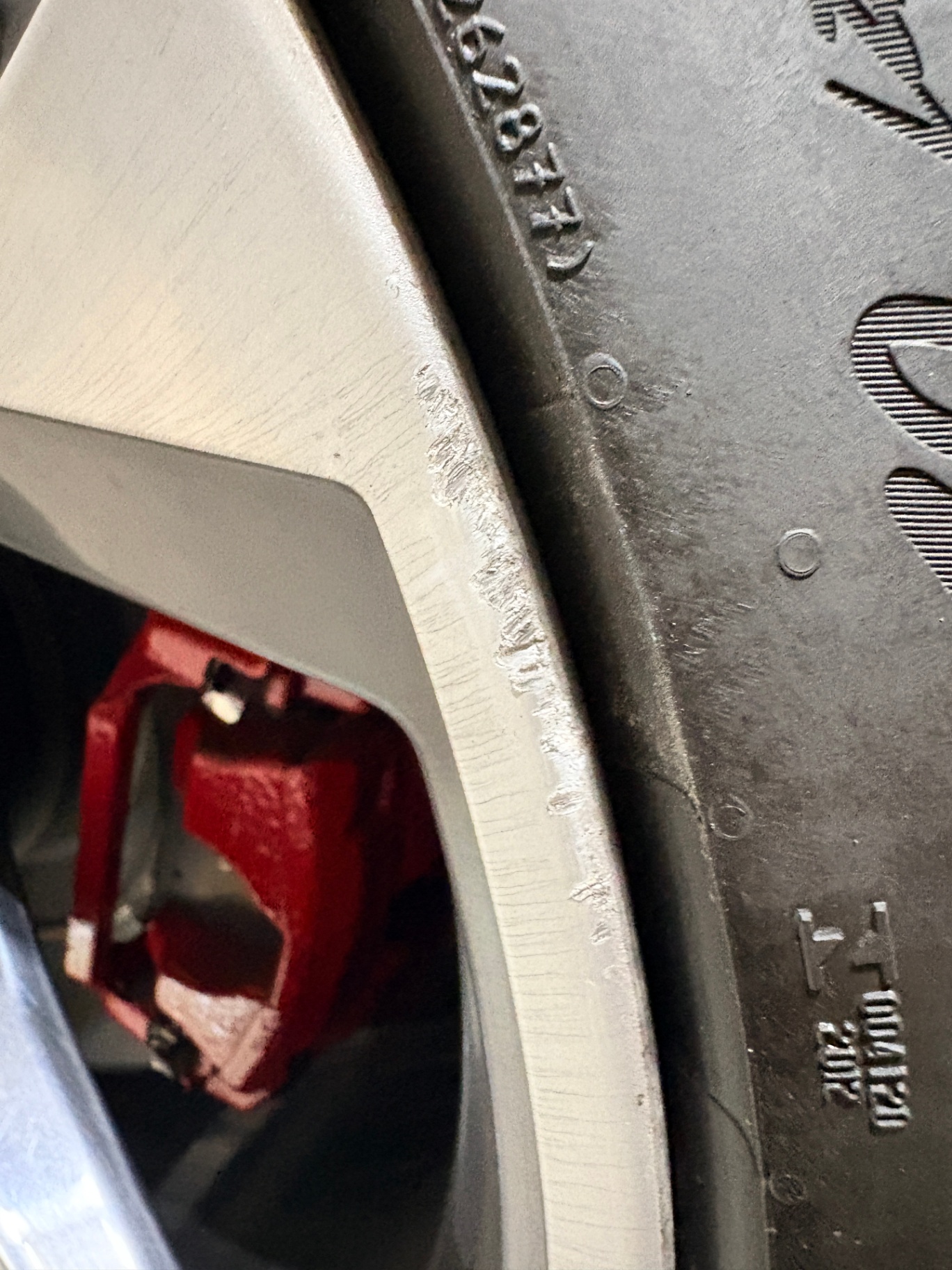 Deep scrapes and gouges along the outer edge of a silver alloy wheel