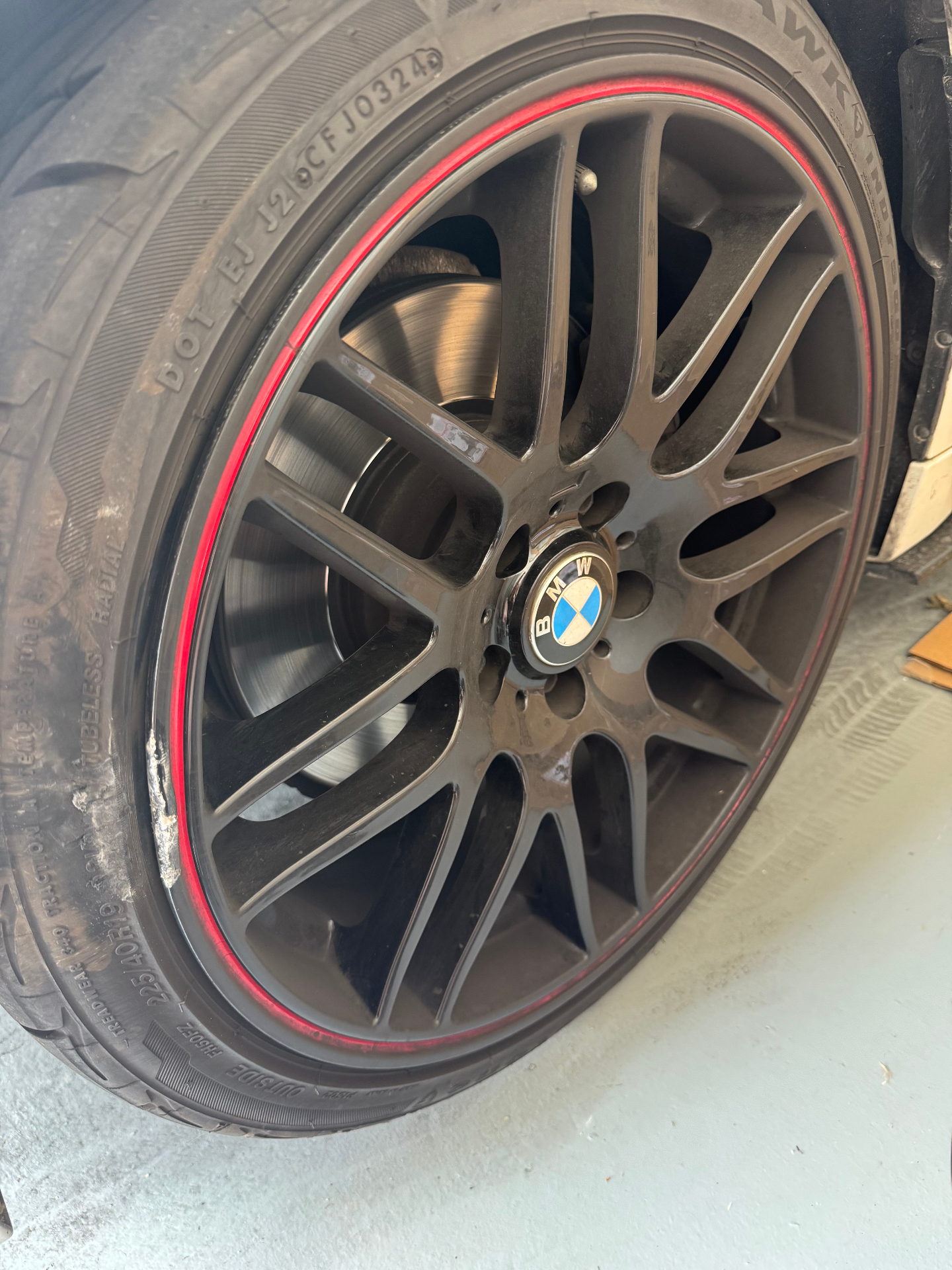 Black BMW wheel with a red stripe and curb rash near the outer lip
