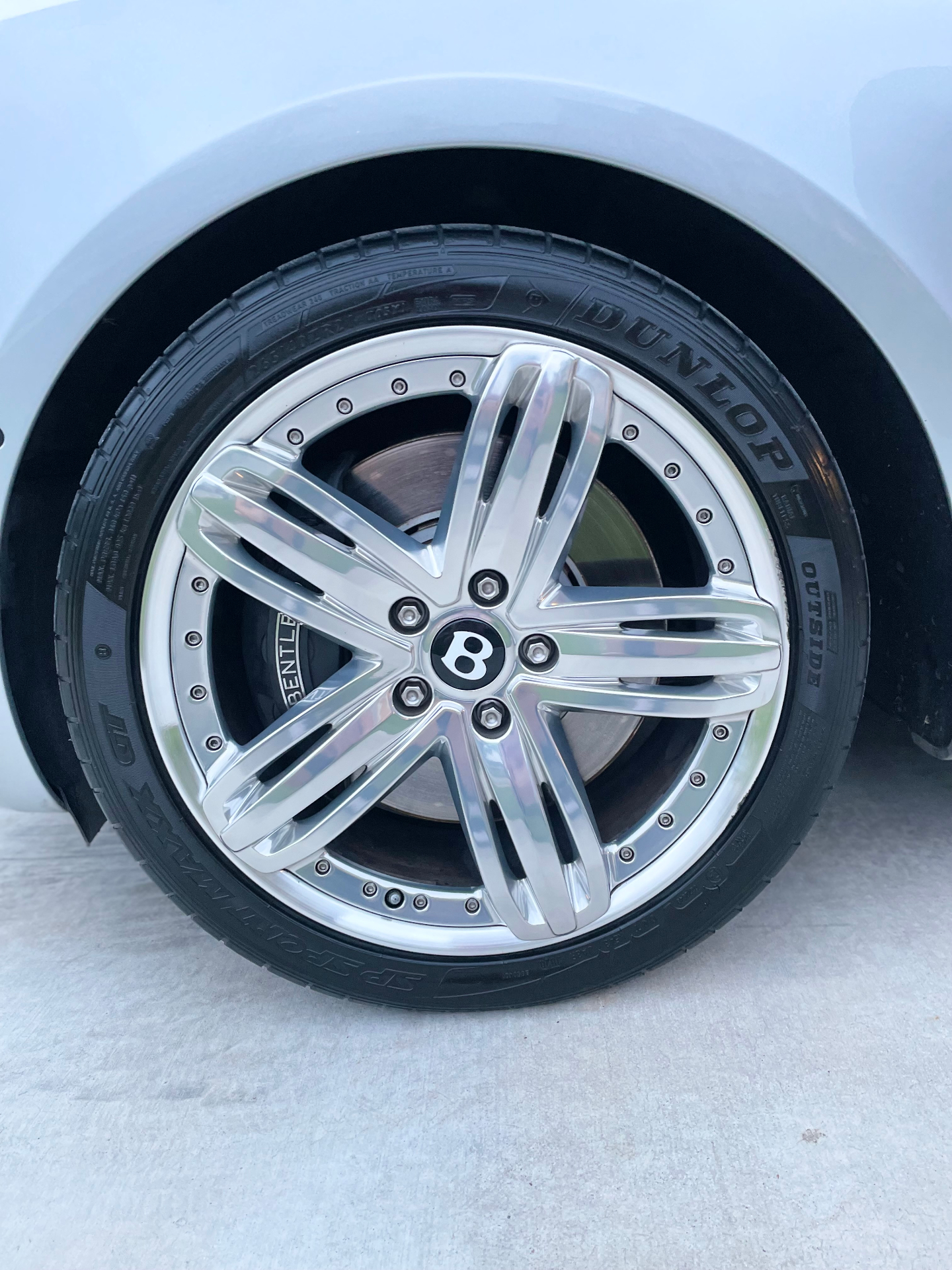 Bentley multi-piece wheel with visible curb rash on the polished lip