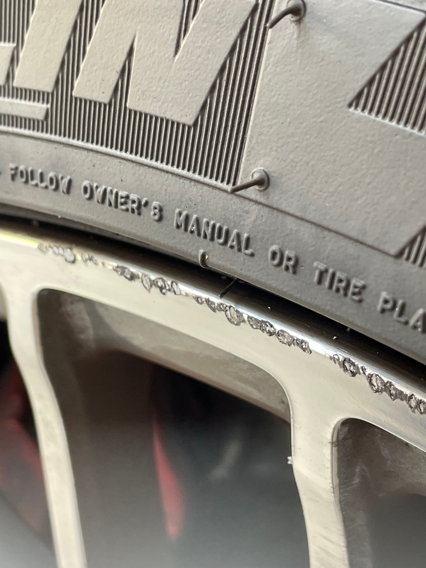 Close-up of a polished wheel lip with repeated curb gouges beneath the tire sidewall